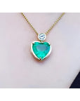 Heart-shaped emerald pendant necklace with a bezel-set diamond on an 18K yellow gold chain.