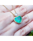 Heart-shaped emerald pendant in 18K yellow gold with a diamond slider bail on a delicate gold chain.