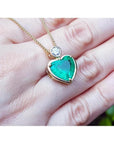 Heart-shaped emerald pendant in 18K yellow gold with a diamond slider bail on a delicate gold chain.