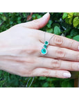 14K white gold emerald journey pendant with three round-cut Colombian emeralds and diamond halo.