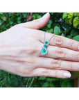 14K white gold emerald journey pendant with three round-cut Colombian emeralds and diamond halo.