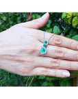 14K white gold emerald journey pendant with three round-cut Colombian emeralds and diamond halo.
