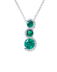 Round cut natural colombian emeralds on a journey style pendant necklace on a white gold chain topside view.