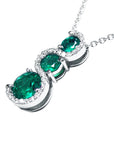 The journey style pendant necklace with three round cut natural colombian emeralds displaying its top and side profile view.
