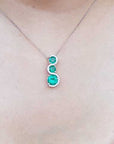 A natural emerald journey necklace on a person's neck against a neutral background.
