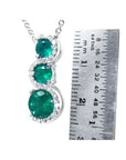 14K white gold emerald journey pendant with three round Colombian emeralds and diamonds on a twisted path.