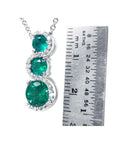 14K white gold emerald journey pendant with three round Colombian emeralds and diamonds on a twisted path.