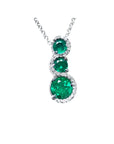 Three round cut natural colombian emerald pendant journey necklace with white gold chain on a topside view position.