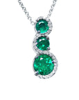 Three round cut natural colombian emerald pendant journey necklace with white gold chain on a topside view position.