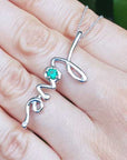 A 14K Solid gold emerald love pendant held between fingers.