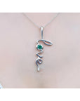 14K white gold "Love" script pendant necklace with a round cut Colombian emerald.