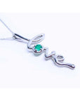 A white gold necklace with a script love pendant featuring an emerald stone on a white background.
