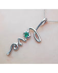 14K white gold "love" script pendant with a round Colombian emerald, on a delicate chain.