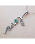 14K white gold "love" script pendant with a round Colombian emerald, on a delicate chain.