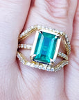 A close-up of an emerald ring on a finger top side view.