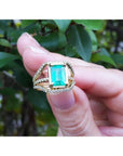 18K yellow gold engagement ring with a rectangular emerald and three rows of diamonds.
