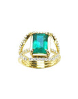 Emerald engagement ring in 18K yellow gold with a rectangular green emerald and three rows of diamonds.