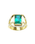 Emerald engagement ring in 18K yellow gold with a rectangular green emerald and three rows of diamonds.