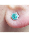 An earlobe dressing a natural emerald stud earring with a geometric halo diamond.