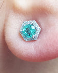 An earlobe dressing a natural emerald stud earring with a geometric halo diamond.