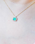 Emerald-cut emerald necklace east west orientation encircled in a halo of natural diamonds, crafted in 14k yellow gold