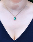 Women's emerald and diamond necklace emerald-cut natural emerald deep green bluish color, encircled by a halo diamond