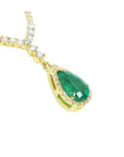 left side of gold necklace with a green emerald teardrop pendant on a white background