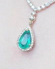 magnification of women's emerald necklace high quality pear cut in 18k yellow gold, encircled by a halo diamond