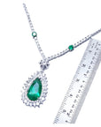 Pear cut emerald necklace with double diamond halo, set in 18K white gold, shown with ruler.