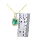 14K gold emerald cut Colombian emerald necklace with halo diamonds, shown next to a ruler.