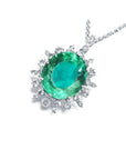 Oval emerald pendant with diamond halo in 14K white gold.