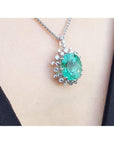 Emerald pendant necklace on a person's neck with a plain background
