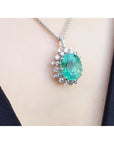 Emerald pendant necklace on a person's neck with a plain background