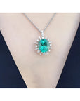 Oval emerald pendant with diamond halo on a 14K white gold chain, worn on a person.