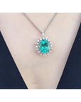 Oval emerald pendant with diamond halo on a 14K white gold chain, worn on a person.