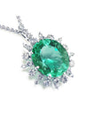 Emerald pendant with halo diamond accents in white gold on a topside position.