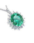 Emerald pendant with halo diamond accents in white gold on a topside position.