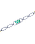 A white gold paperclip bracelet with emerald and diamonds at center and gold accents top view.