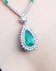 Pear cut emerald necklace with double diamond halo in 18K white gold.