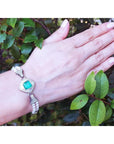 18K white gold emerald and pearl bracelet with a bezel-set Colombian emerald, diamonds, and pearls on a wrist.