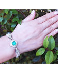 18K white gold emerald and pearl bracelet with a bezel-set Colombian emerald, diamonds, and pearls on a wrist.