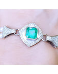 Emerald-cut Colombian emerald and pearls bracelet crafted in 18k white gold on a wrist.