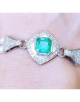 Emerald-cut Colombian emerald and pearls bracelet crafted in 18k white gold on a wrist.