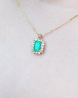 Gold necklace with a Muzo colombian emerald pendant on a person's neck.
