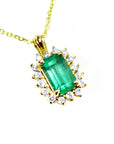 Gold necklace with a natural emerald and diamond accents on a topside view.
