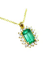 Gold necklace with a natural emerald and diamond accents on a topside view.
