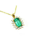 Gold necklace with a natural emerald and diamond accents on a topside view.