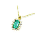 14K yellow gold pendant with a rectangular emerald surrounded by a halo of natural diamonds.