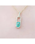 18K yellow gold emerald-cut emerald pendant with diamond halo on a delicate chain.
