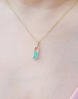 Gold necklace with a real colombian emerald pendant on a person wearing a pink top.